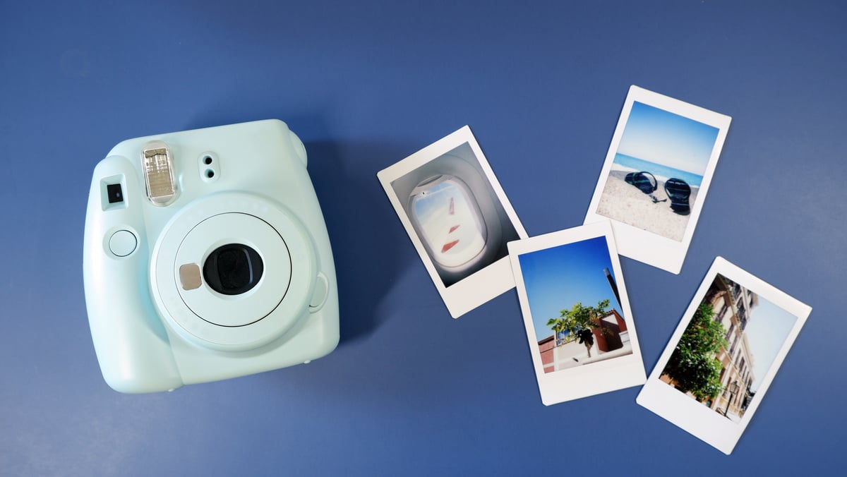 Instant camera with photos on blue background